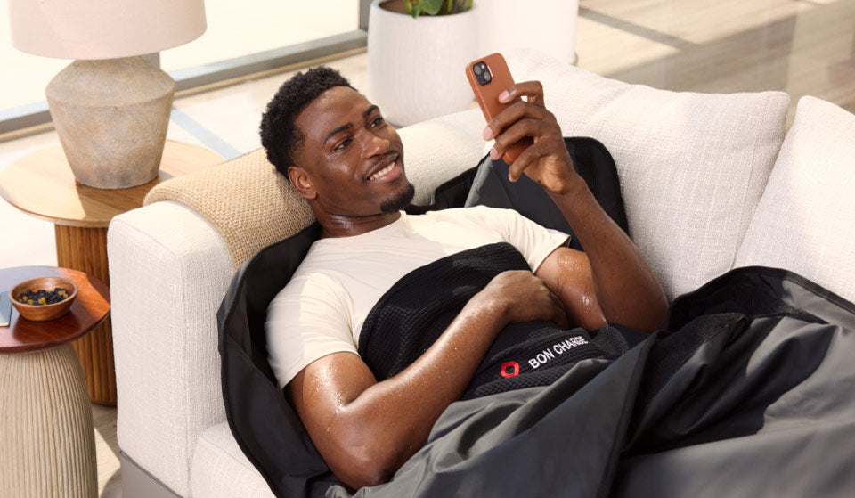 Male Laying On Sofa In Sauna Blanket Scrolling On Phone