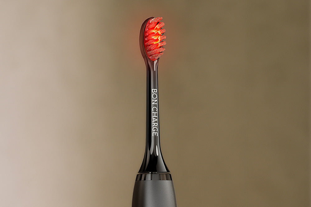 Black electric toothbrush head with red bristles on a beige background